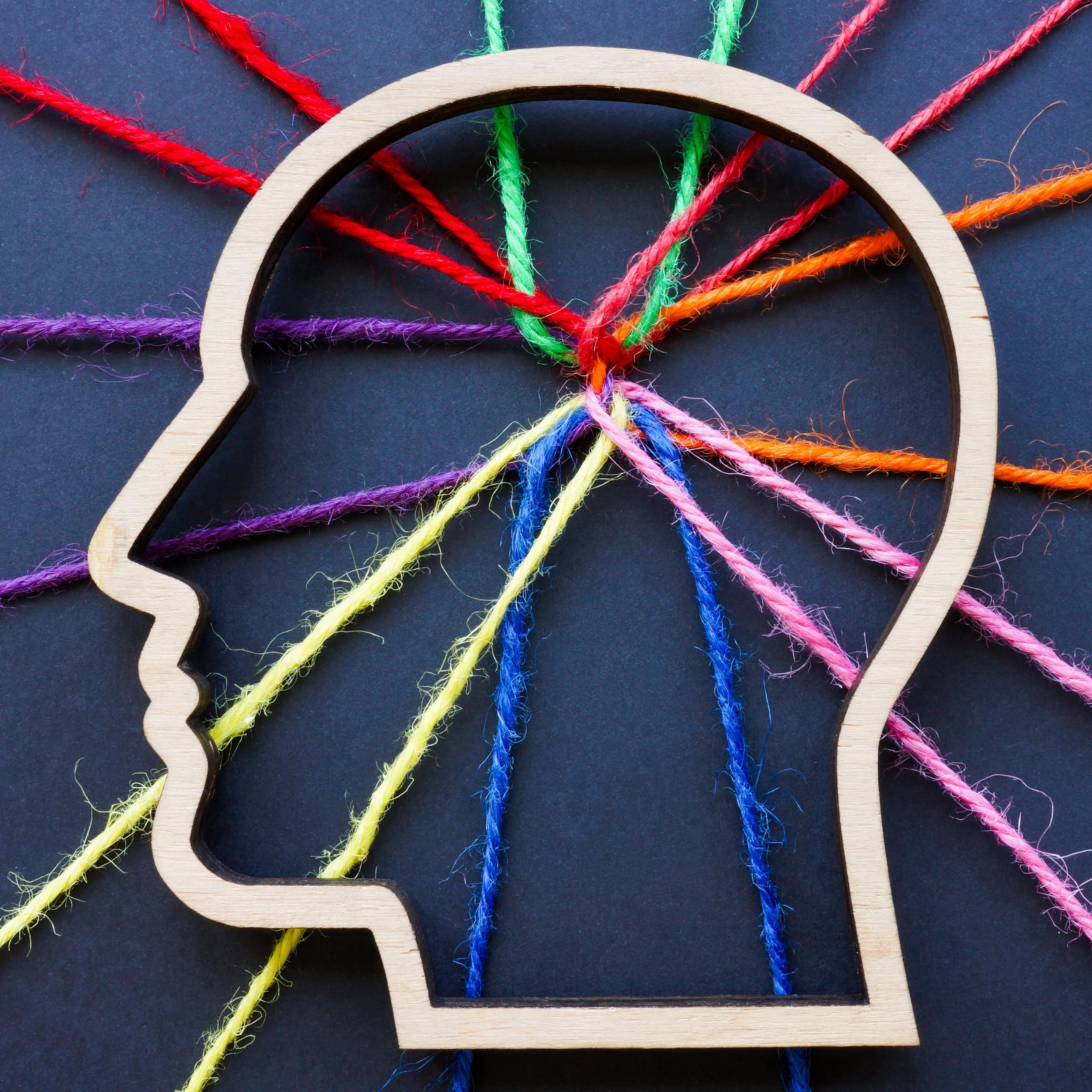 An outline of a human head with connected coloured threads criss-crossing