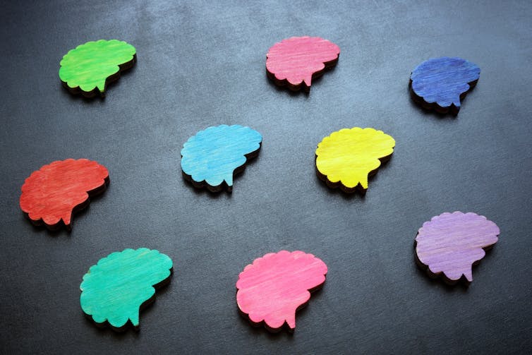 Multicolored figures of the brain on a dark surface.