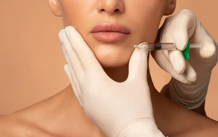 woman's face, injection near lips with gloved hand of medical professional
