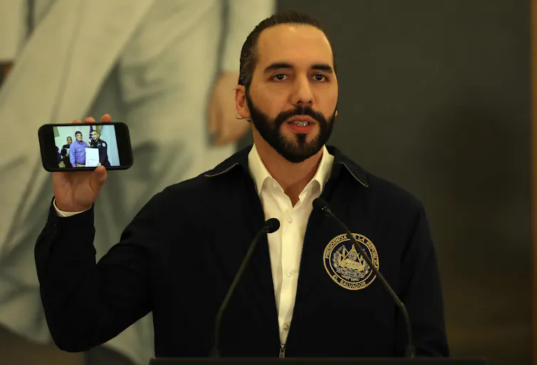El Salvador's president, Nayib Bukele, holds up a phone.