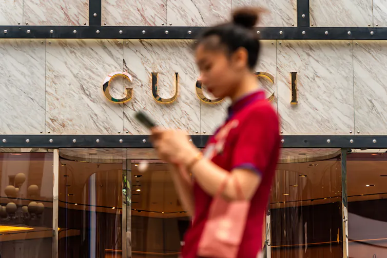 A Chinese woman walking past a Gucci store.