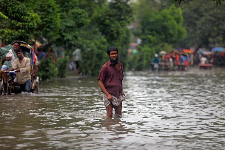 A man stands in a street flooded with water.