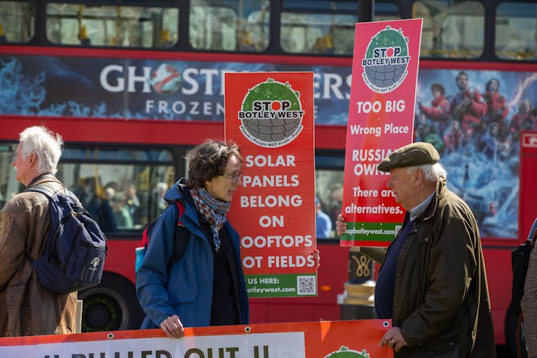 ‘You can’t consume electrical energy’: how rural sun farms turned into the newest battlefront in Britain’s tradition battle 1 Two protesters with London bus in background
