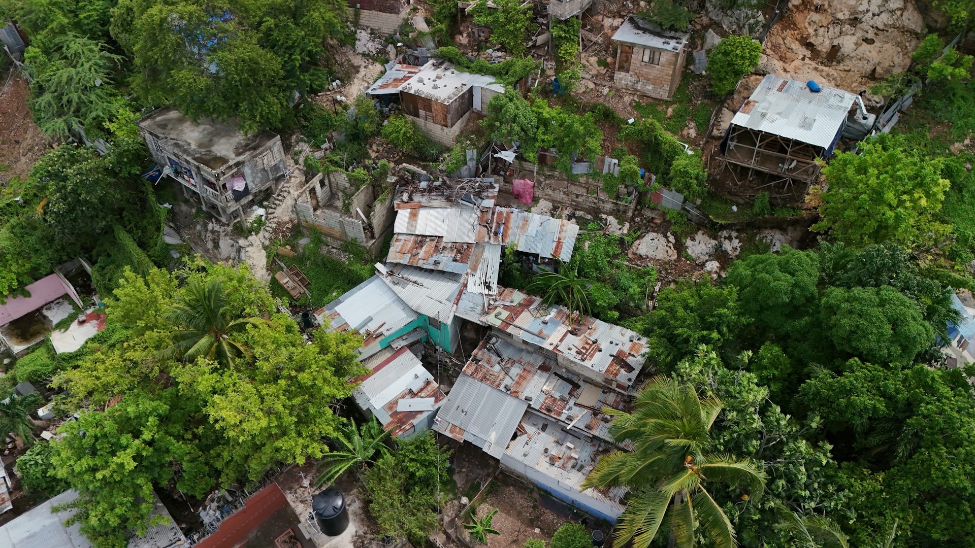 aerial shot of damaged houses on tropical island with palm trees