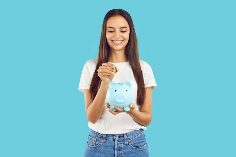 blue background, woman smiling putting coin into blue piggy bank