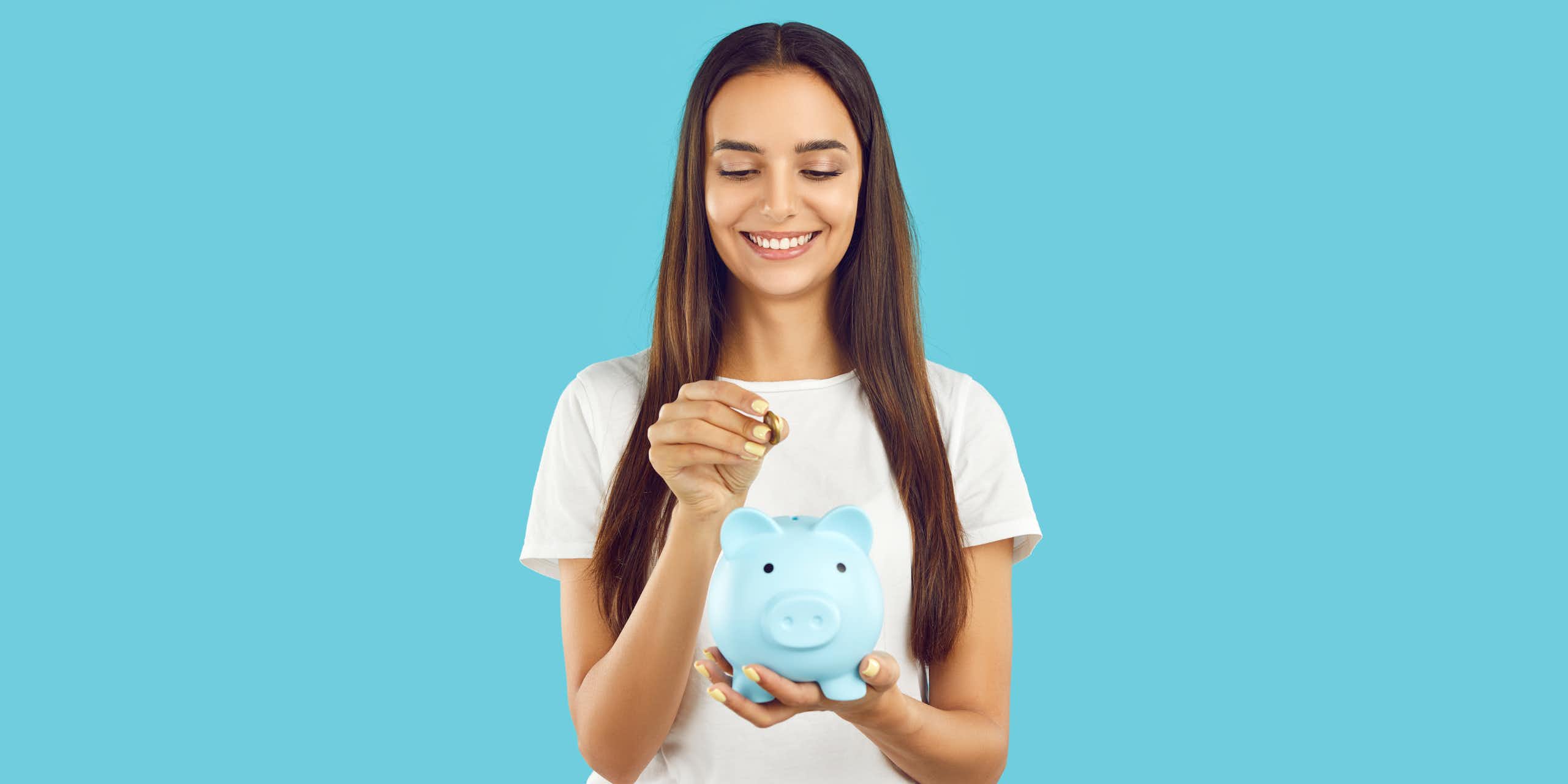 blue background, woman smiling putting coin into blue piggy bank