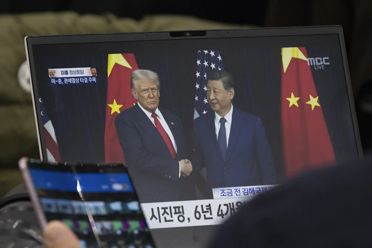 A laptop screen displaying Donald Trump and Xi Jinping shaking hands.