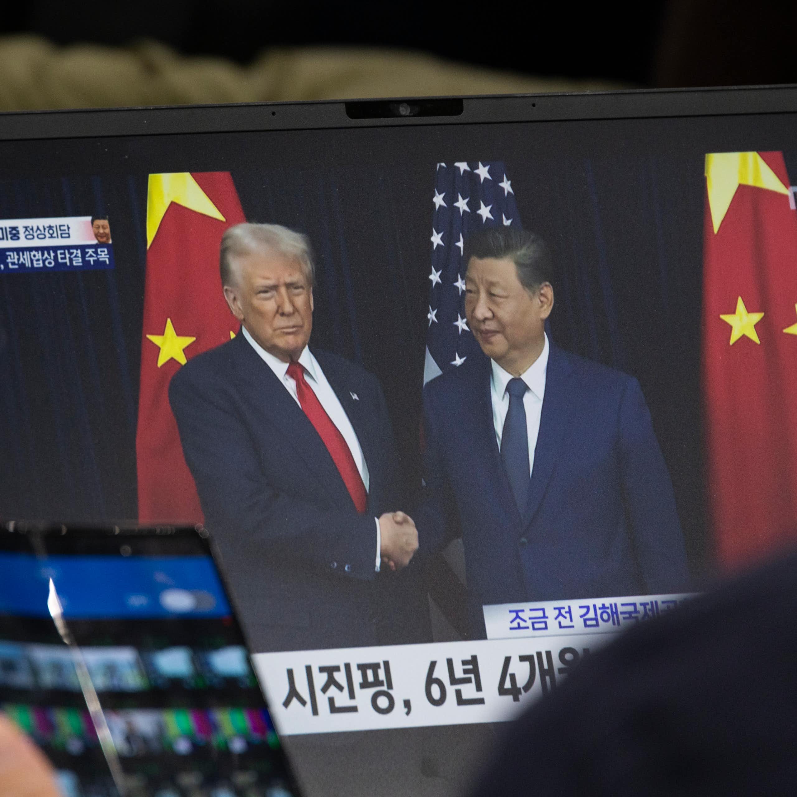 A laptop screen displaying Donald Trump and Xi Jinping shaking hands.