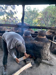 Bebe tequila y mezcal de manera sustentable en Día de Muertos 2 un hombre carga leña en un estante