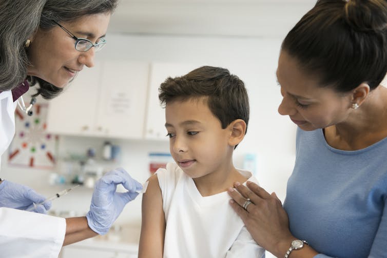 Child gets a vaccine from his doctor, with his mother by his side.