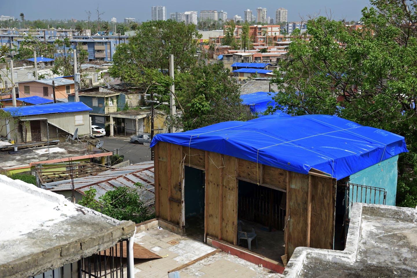 Several houses covered with blue tarps to keep the rain out