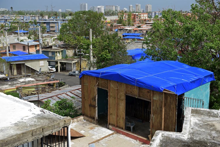 Several houses covered with blue tarps to keep the rain out