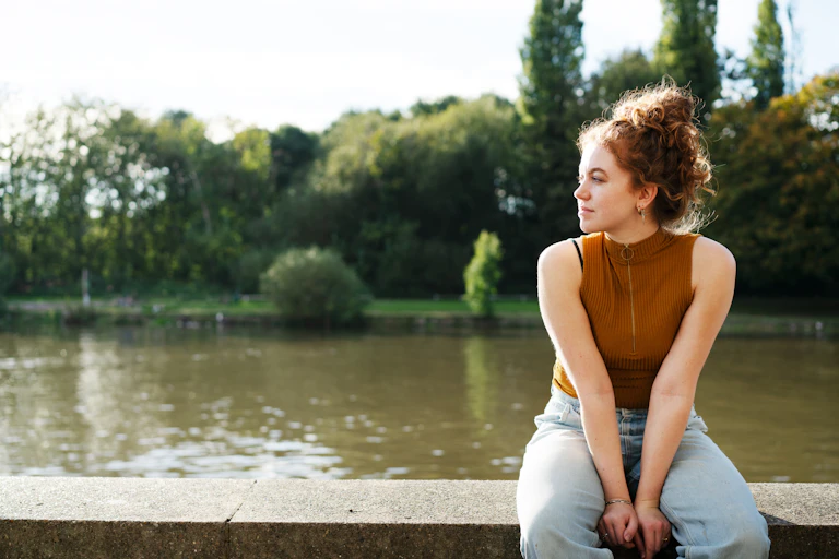 Woman sits on a river wall