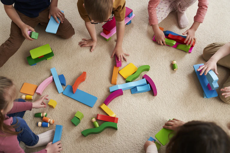 Young children play with coloured blocks.