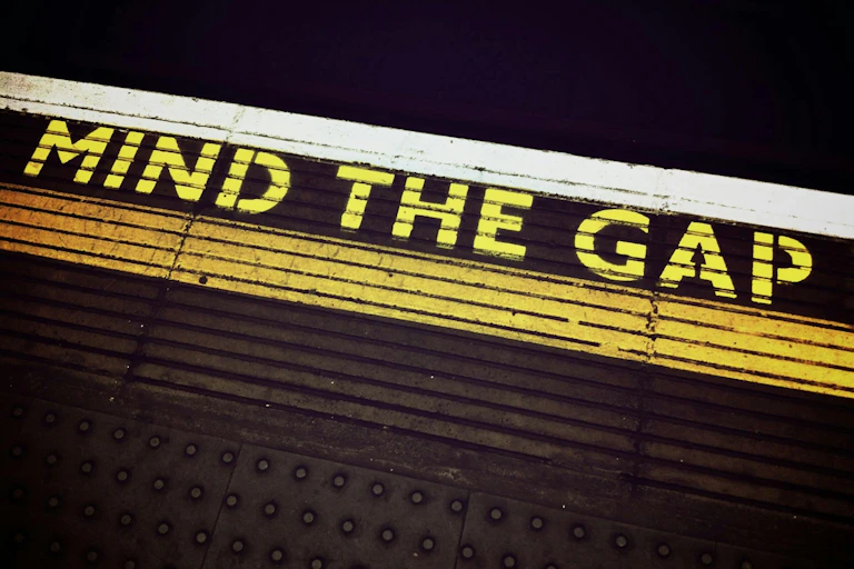 A train platform with the words, "Mind the gap", painted in yellow.
