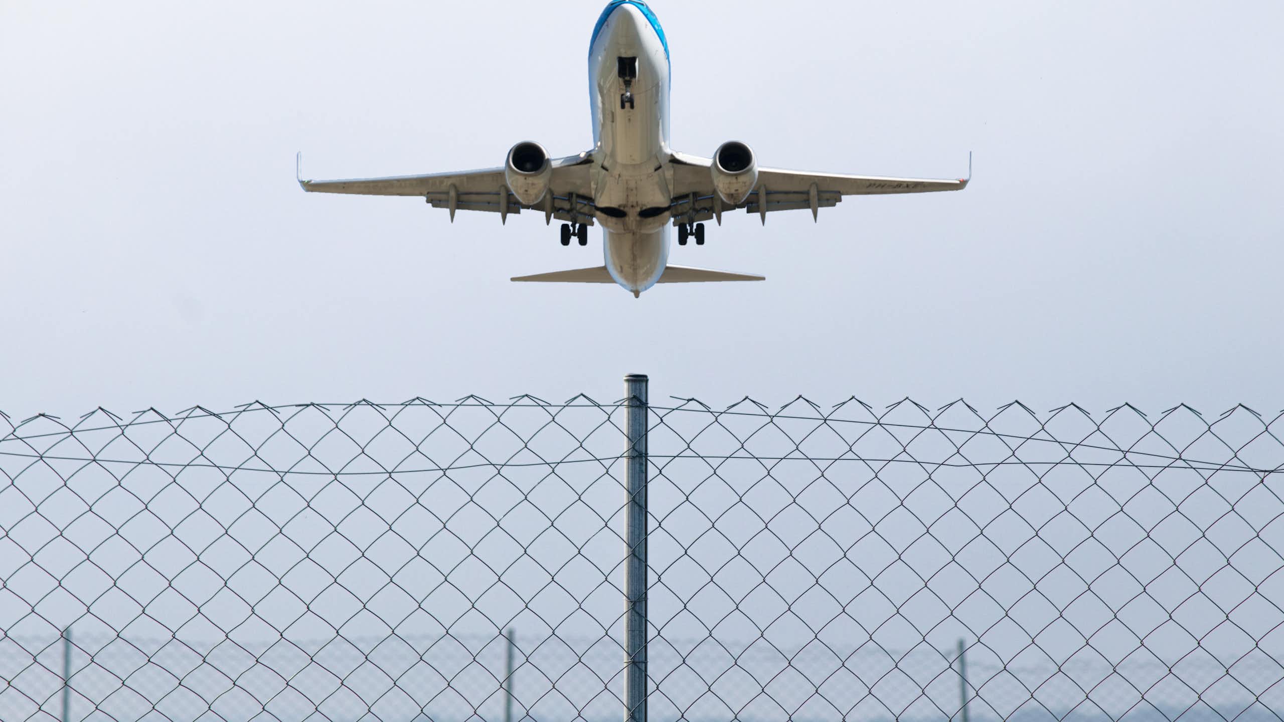 A passenger plane flying over a wire fence