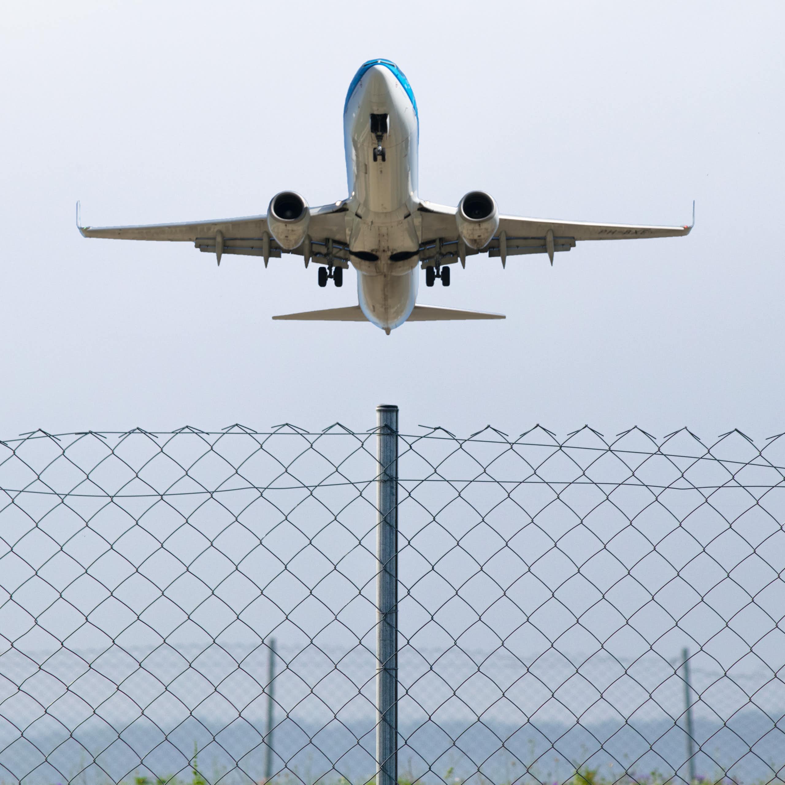 A passenger plane flying over a wire fence