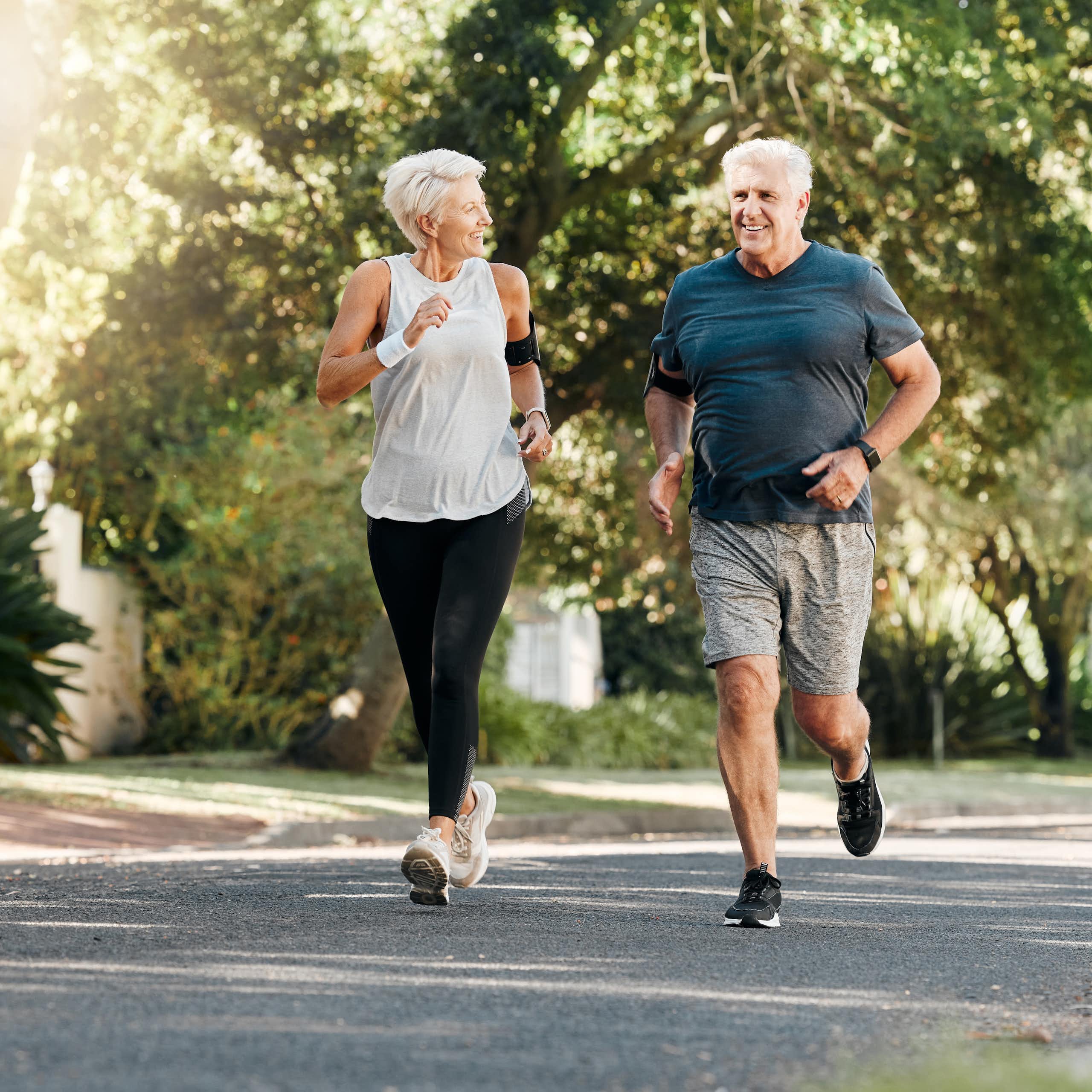 A middle-aged woman and men run through a park together.