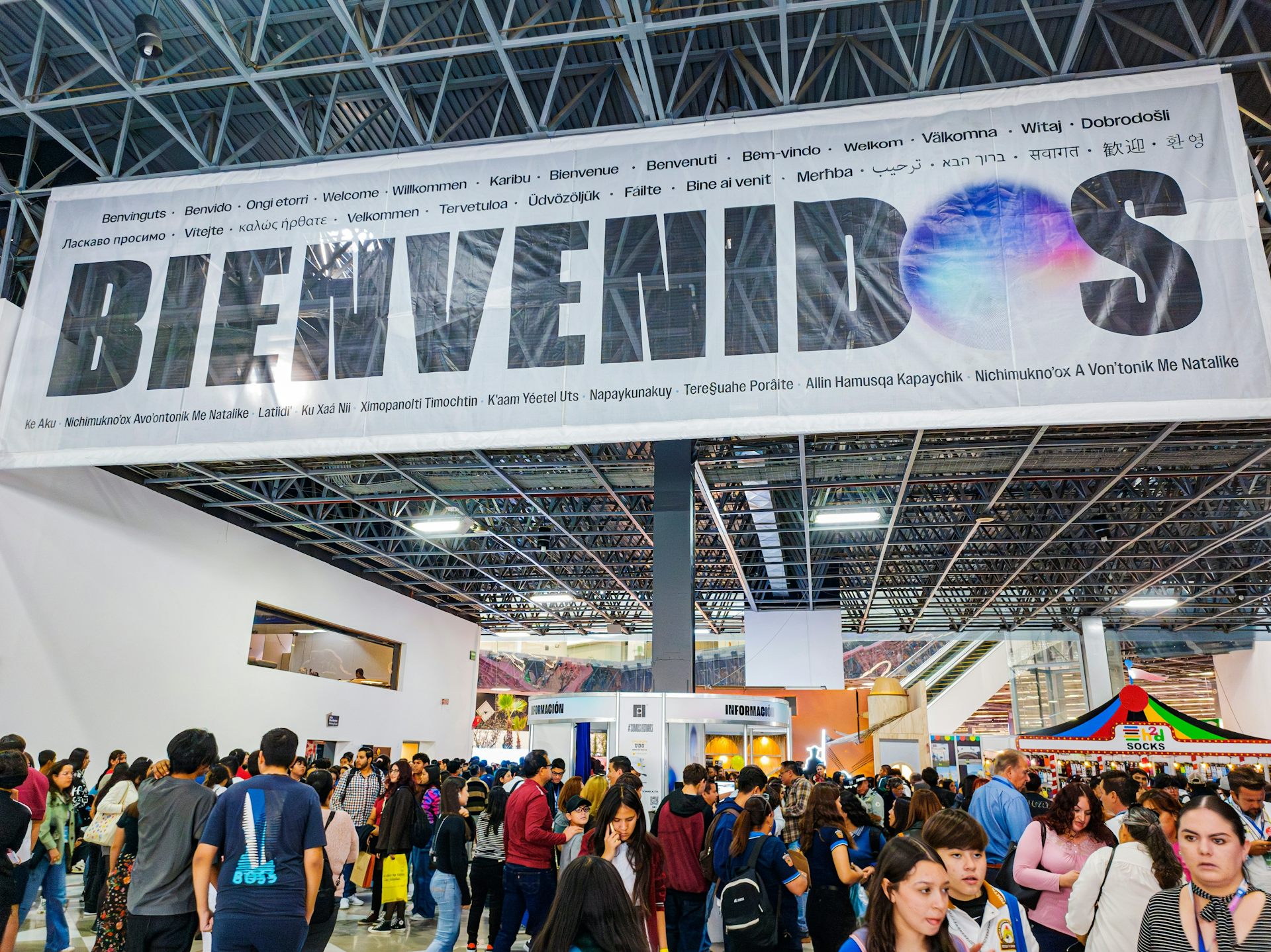 Mucha gente bajo un cartel en el que puede leerse "Bienvenidos"