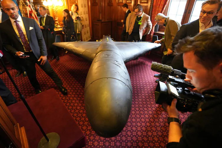 Group of people examining a missile on display in a room