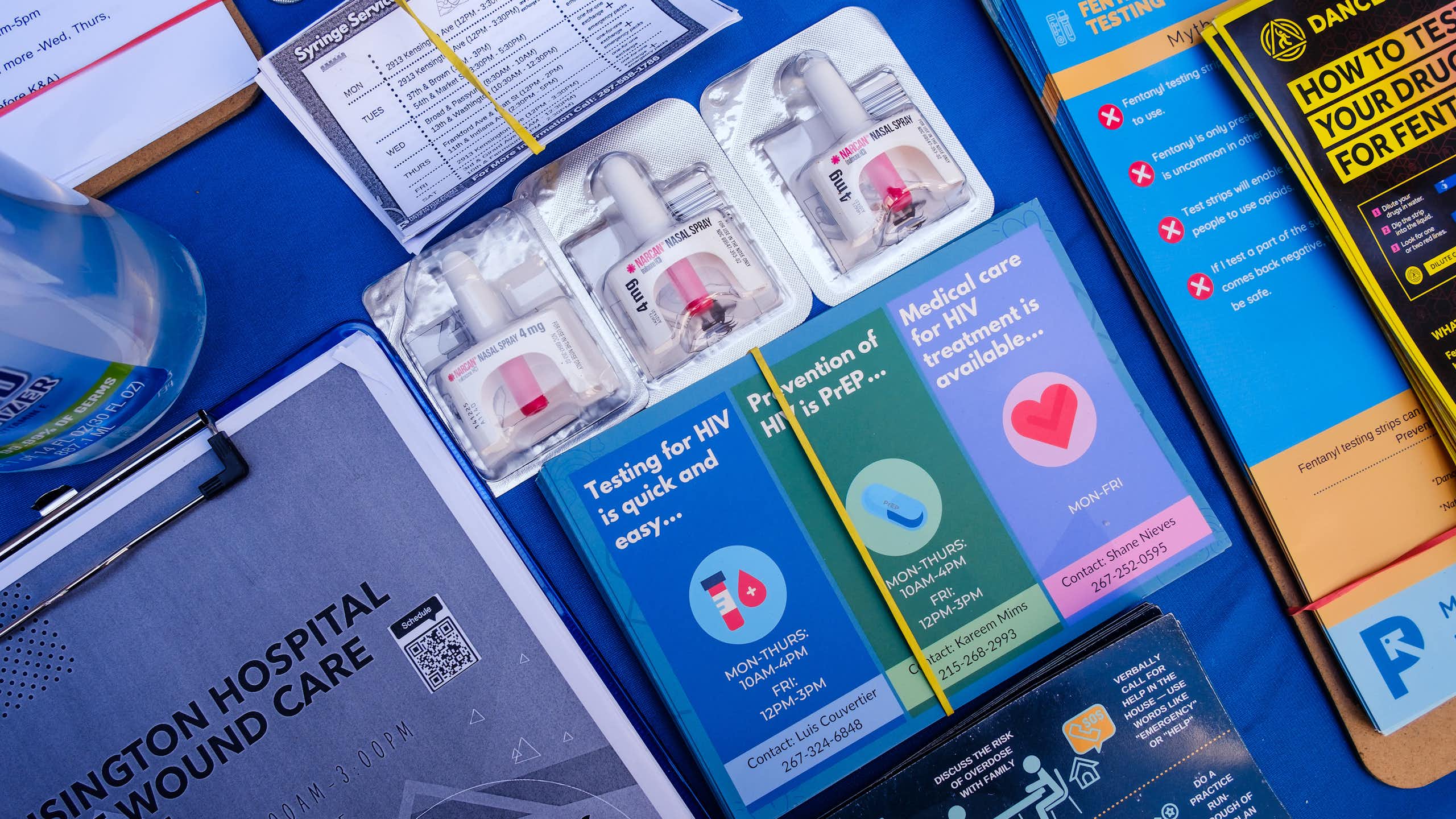 Various papers, brochures and flyers related to opioid addiction are organized on a blue table