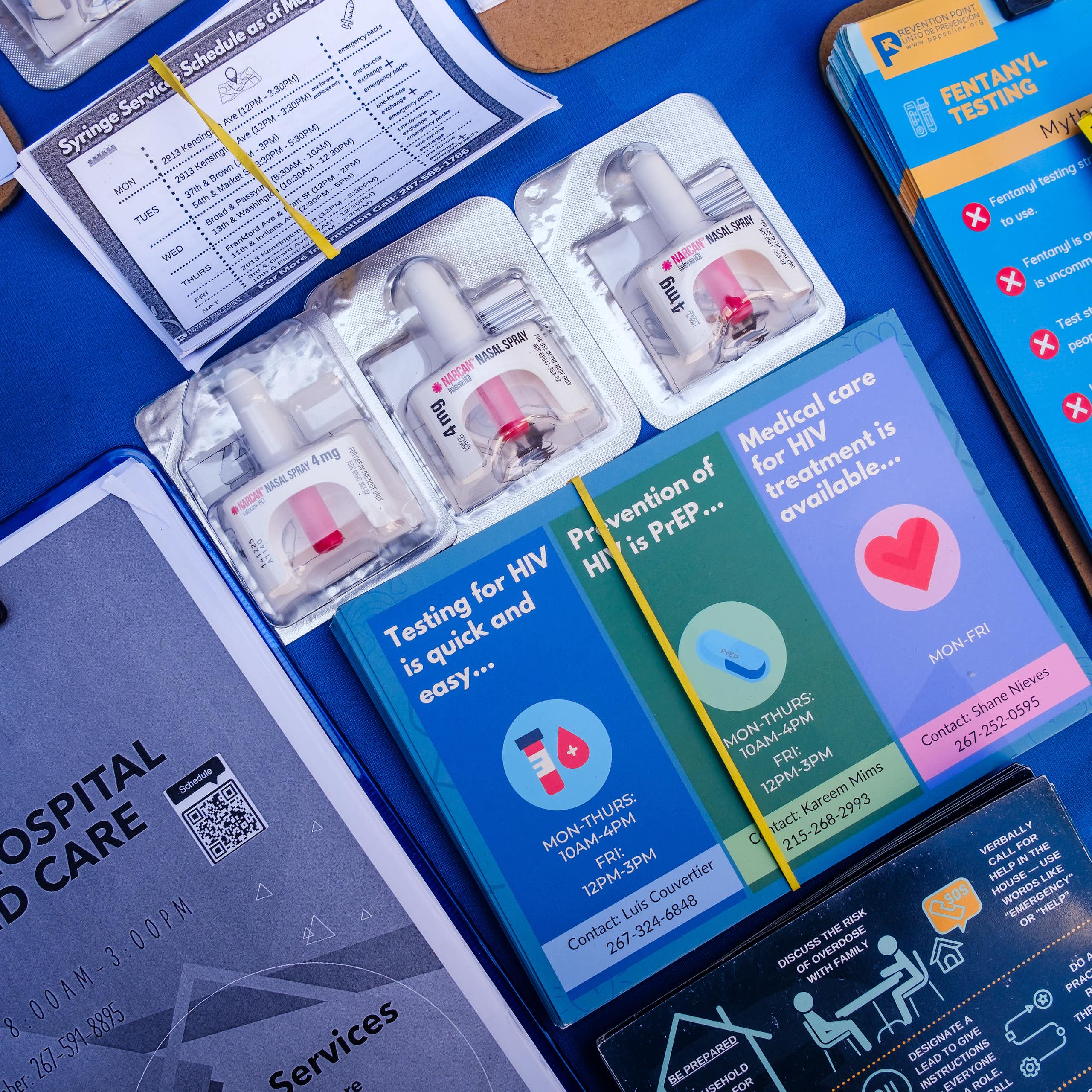Various papers, brochures and flyers related to opioid addiction are organized on a blue table