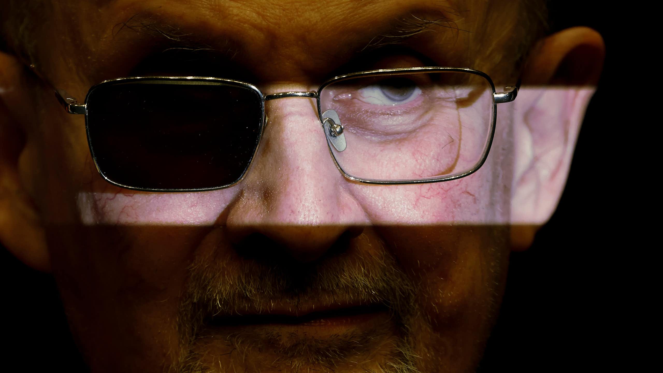 Salman Rushdie wearing glasses with one lens darkened
