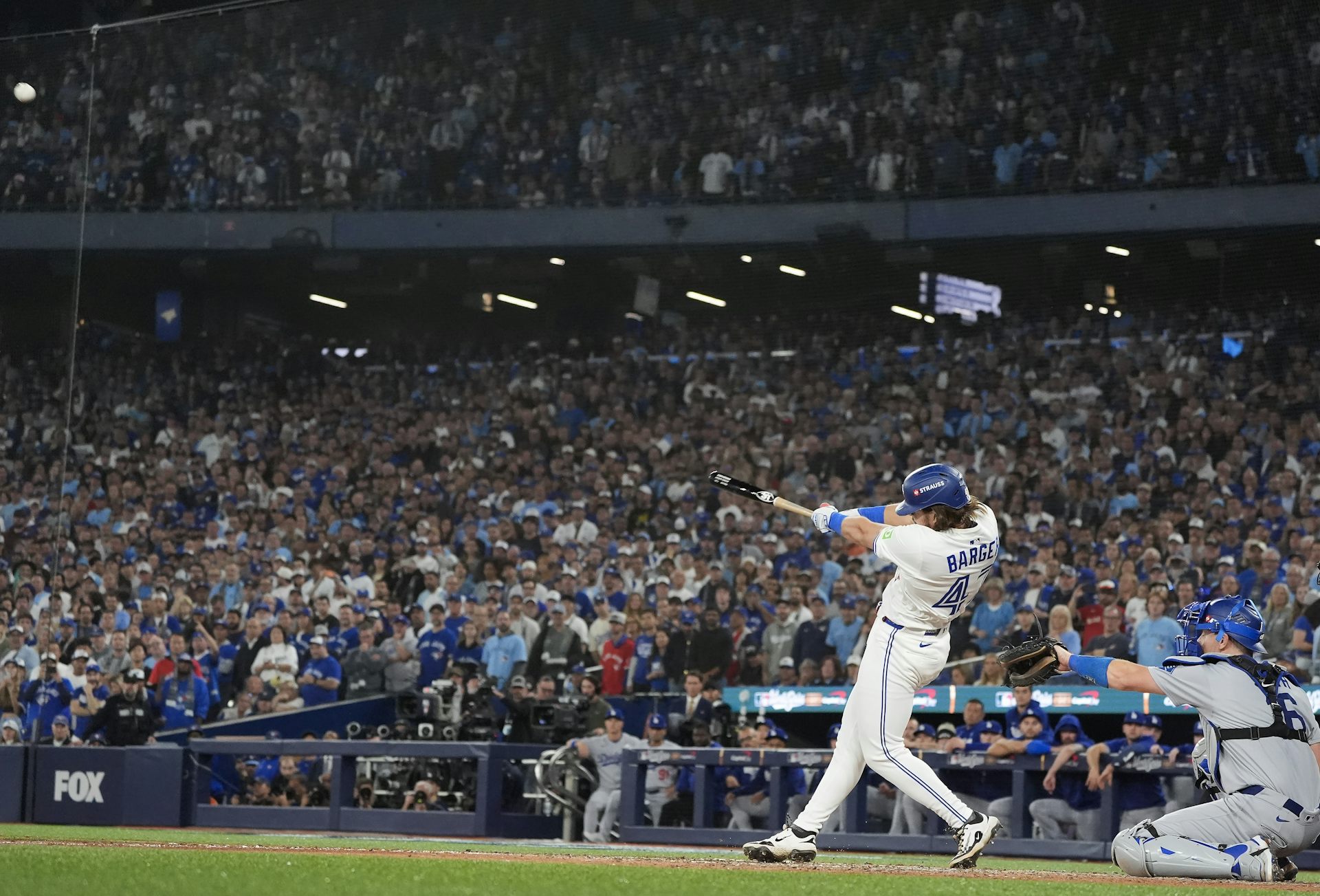 A baseball player swings his bat in front of a full stadium