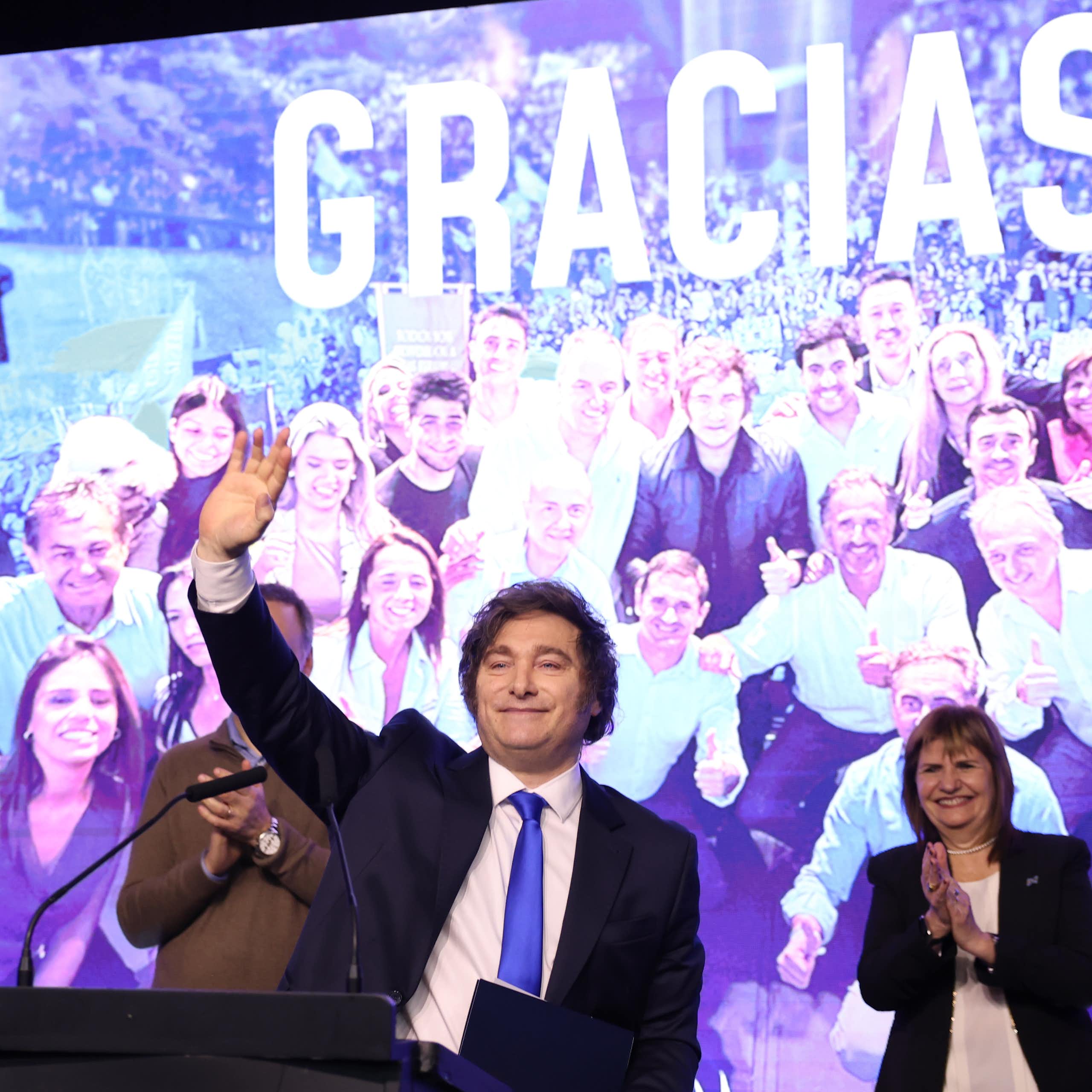 argentinian president javier milei gives a celebratory speech in front of a backdrop reading 'gracias'
