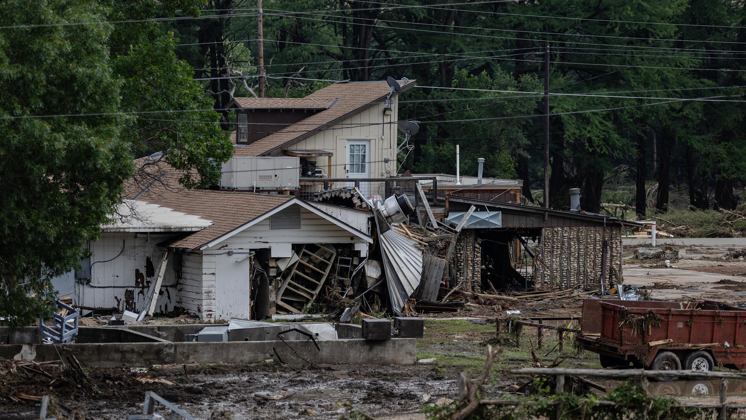 A flood-damaged house is covered in mud and debris.