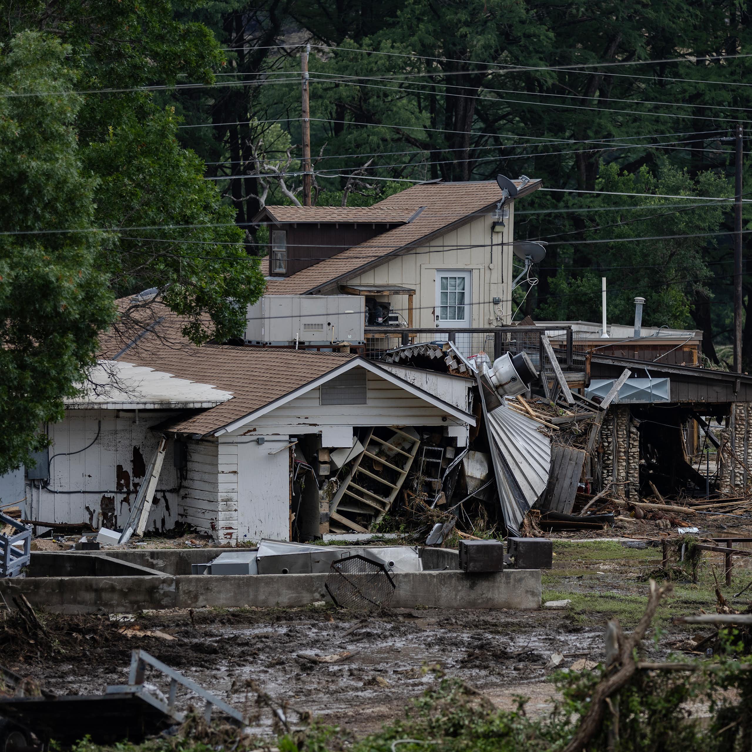 A flood-damaged house is covered in mud and debris.