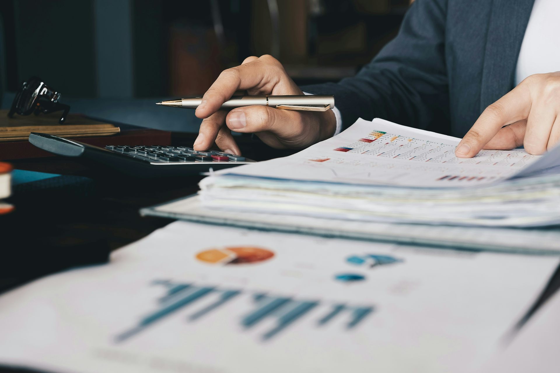 Close up of a person's hands as they sort through financial documents and using a calculator