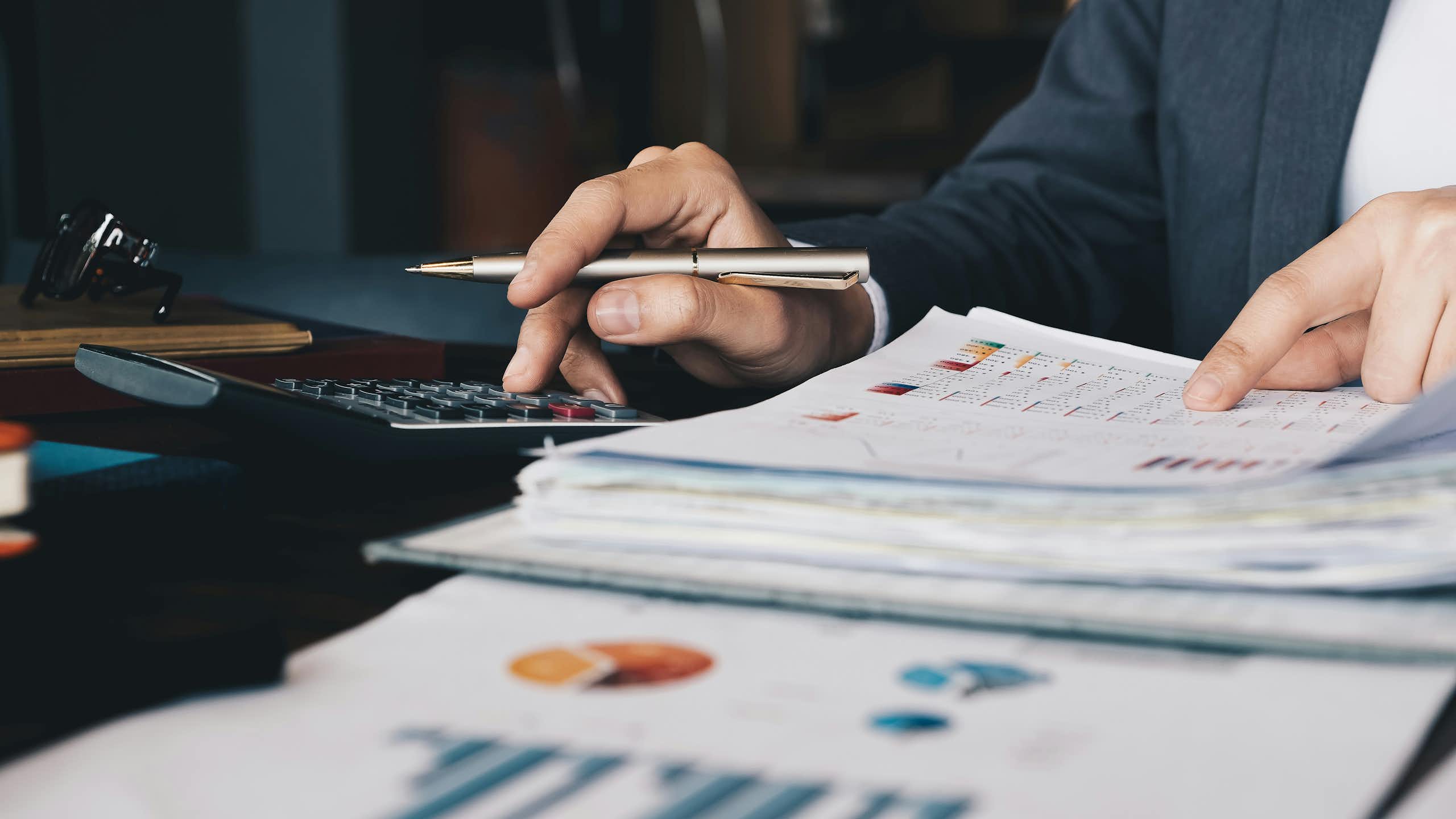 Close up of a person's hands as they sort through financial documents and using a calculator