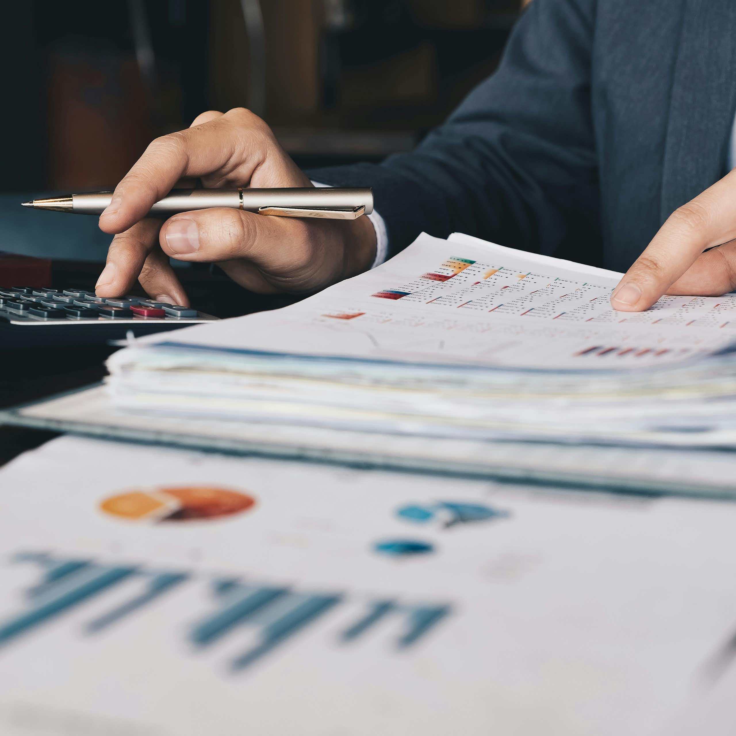 Close up of a person's hands as they sort through financial documents and using a calculator