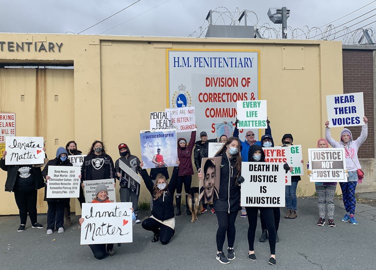 Personas con carteles exigiendo una mejor protección de la salud mental de los presos fuera de la prisión.