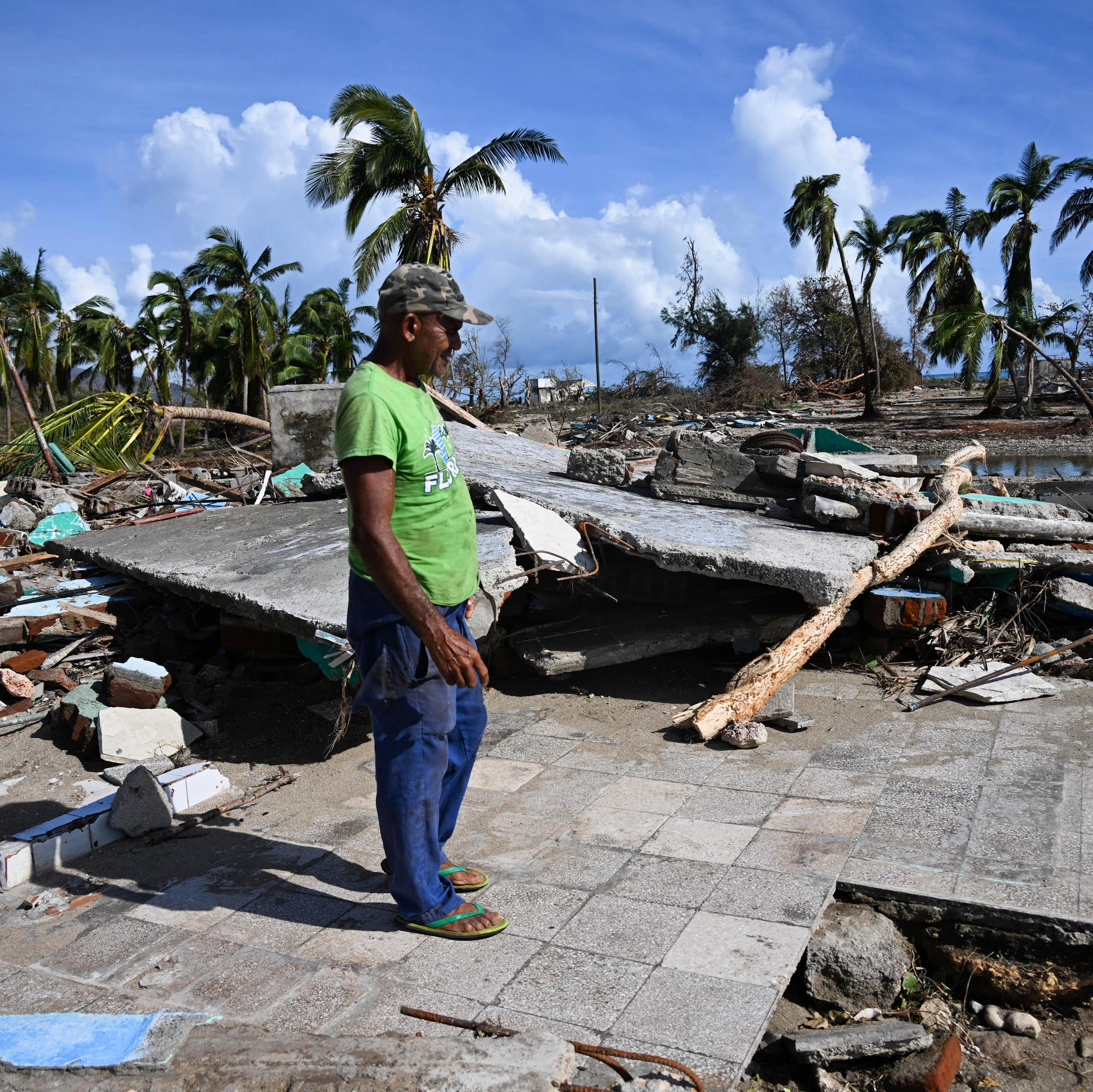 un homme dans un paysage de littoral dévasté par l'ouragan mélissa