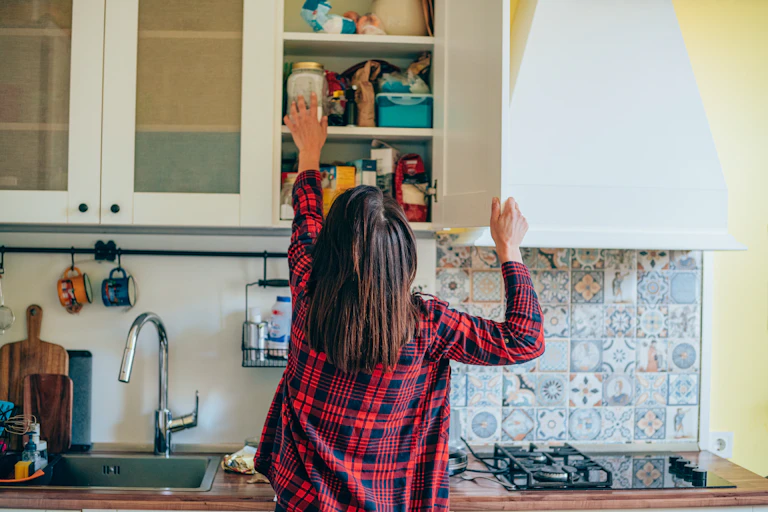 Woman reaches for food in a high cupboard