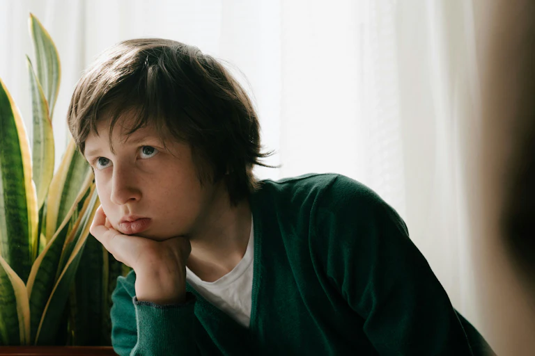 A boy looks glum, with his head in his hand.