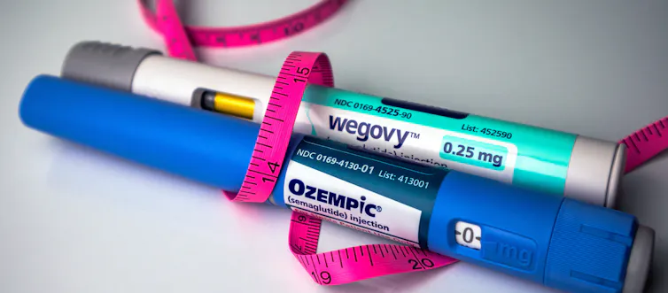 Photo de deux seringues de médicaments, l’une d’Ozempic et l’autre de Wegovy, autour desquelles est enroulé un mètre-ruban magenta.