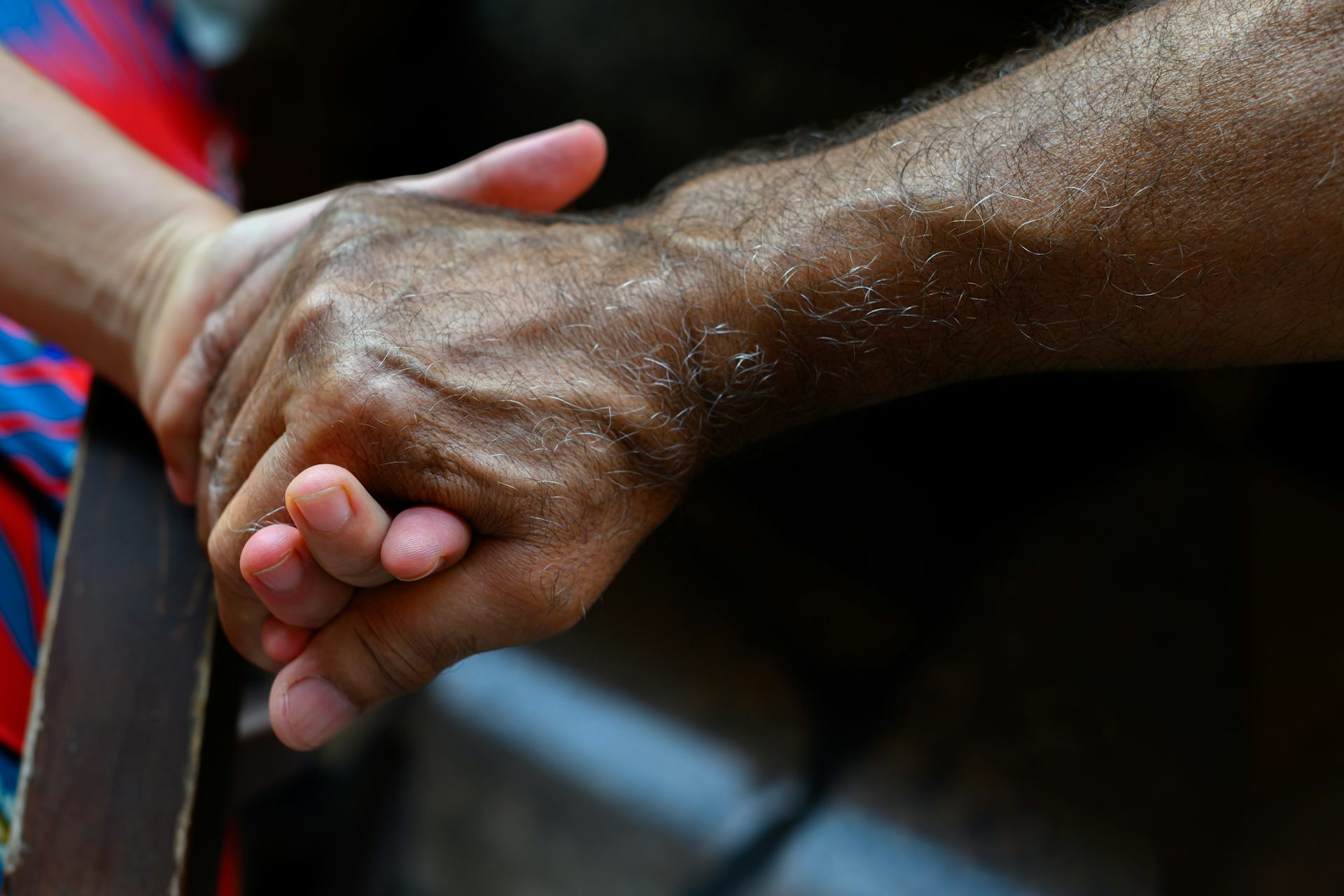 Hands of a woman and an older man clasped together