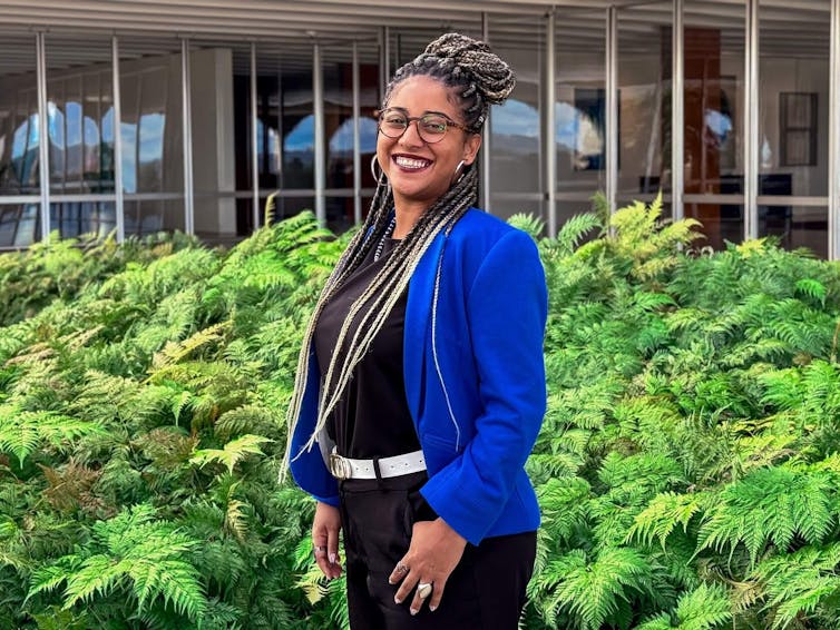woman in blue top, stood outside by green garden