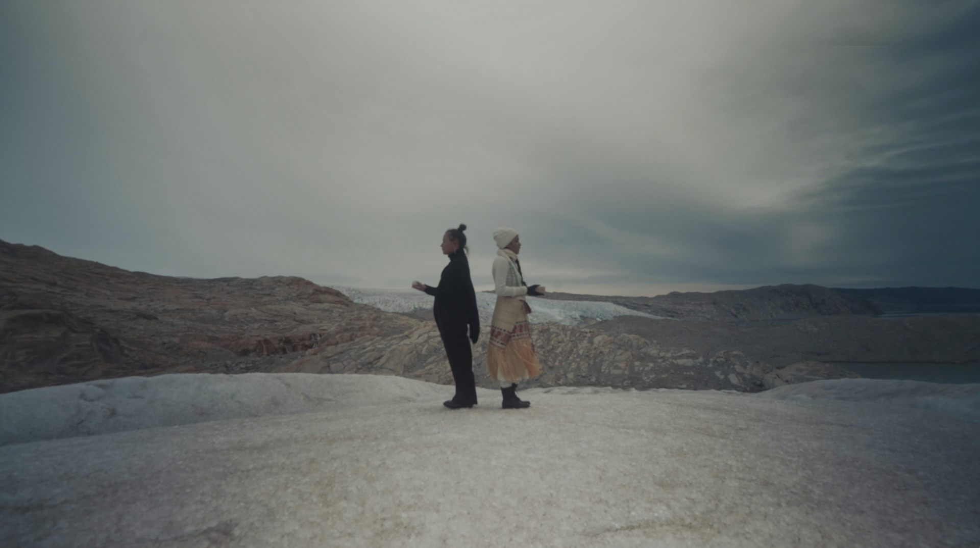 two women standing back to back on deserted landscape