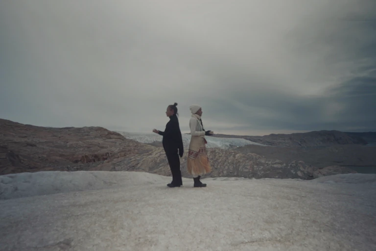 two women standing back to back on deserted landscape