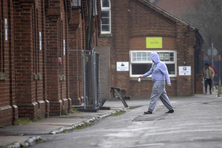 A man in hoodie and joggers walks in Napier Barracks