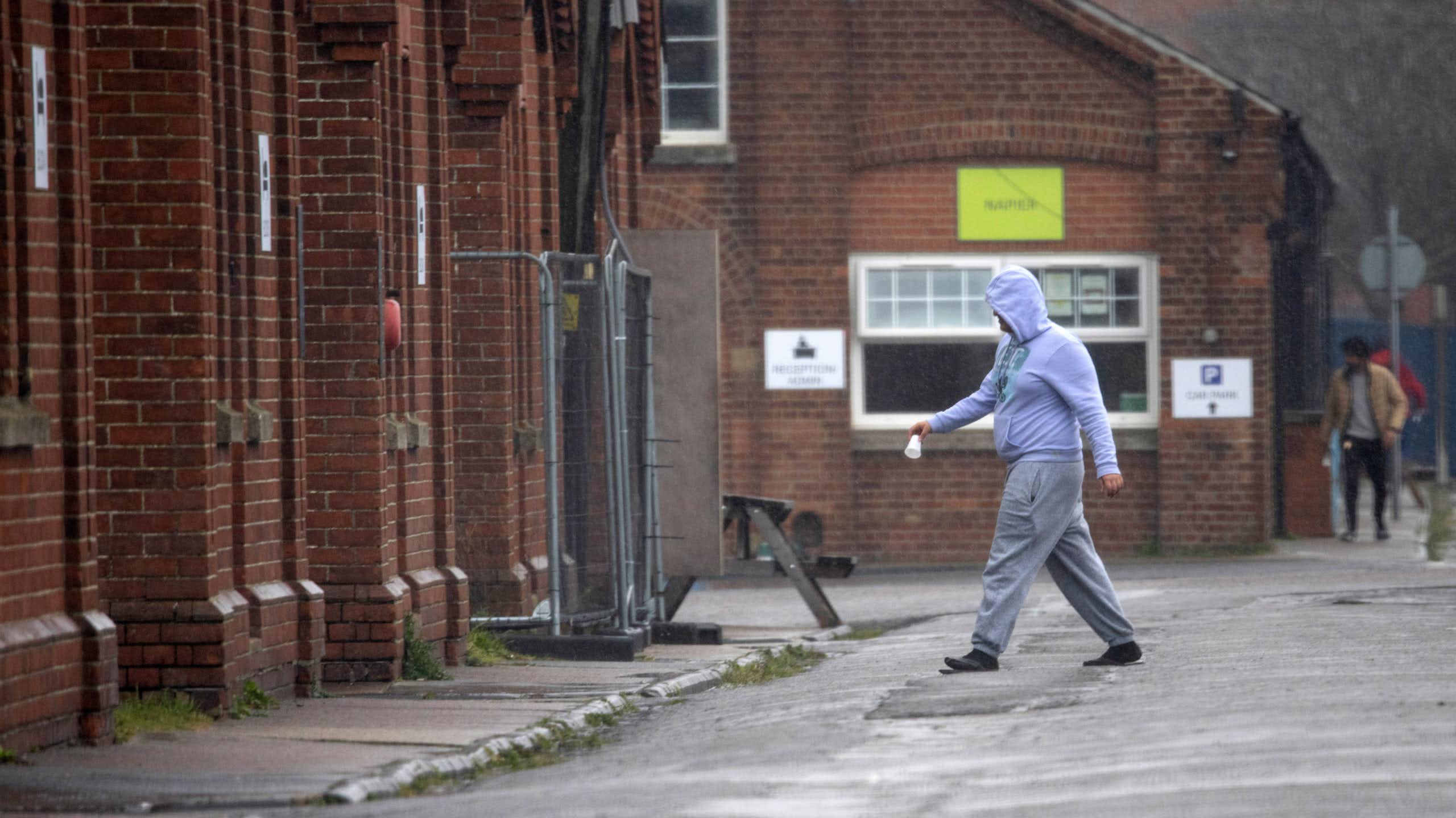 A man in hoodie and joggers walks in Napier Barracks