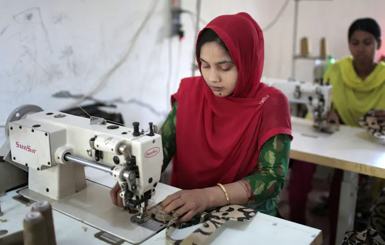 A woman in a head scarf sews with a sewing machine