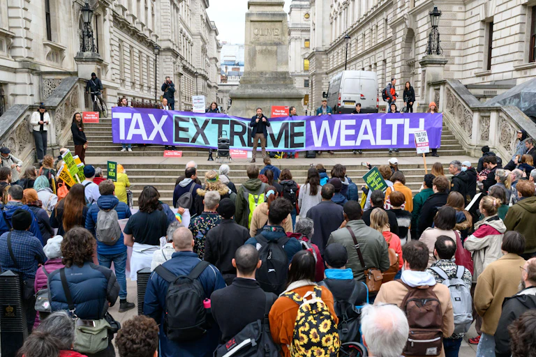 Protesters outside the Treasury in London with a banner calling to 'tax extreme wealth'.