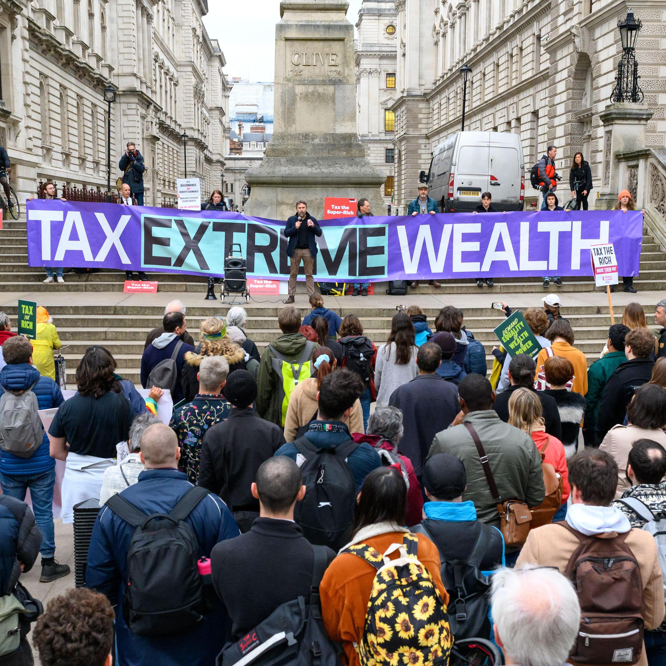 Protesters outside the Treasury in London with a banner calling to 'tax extreme wealth'.