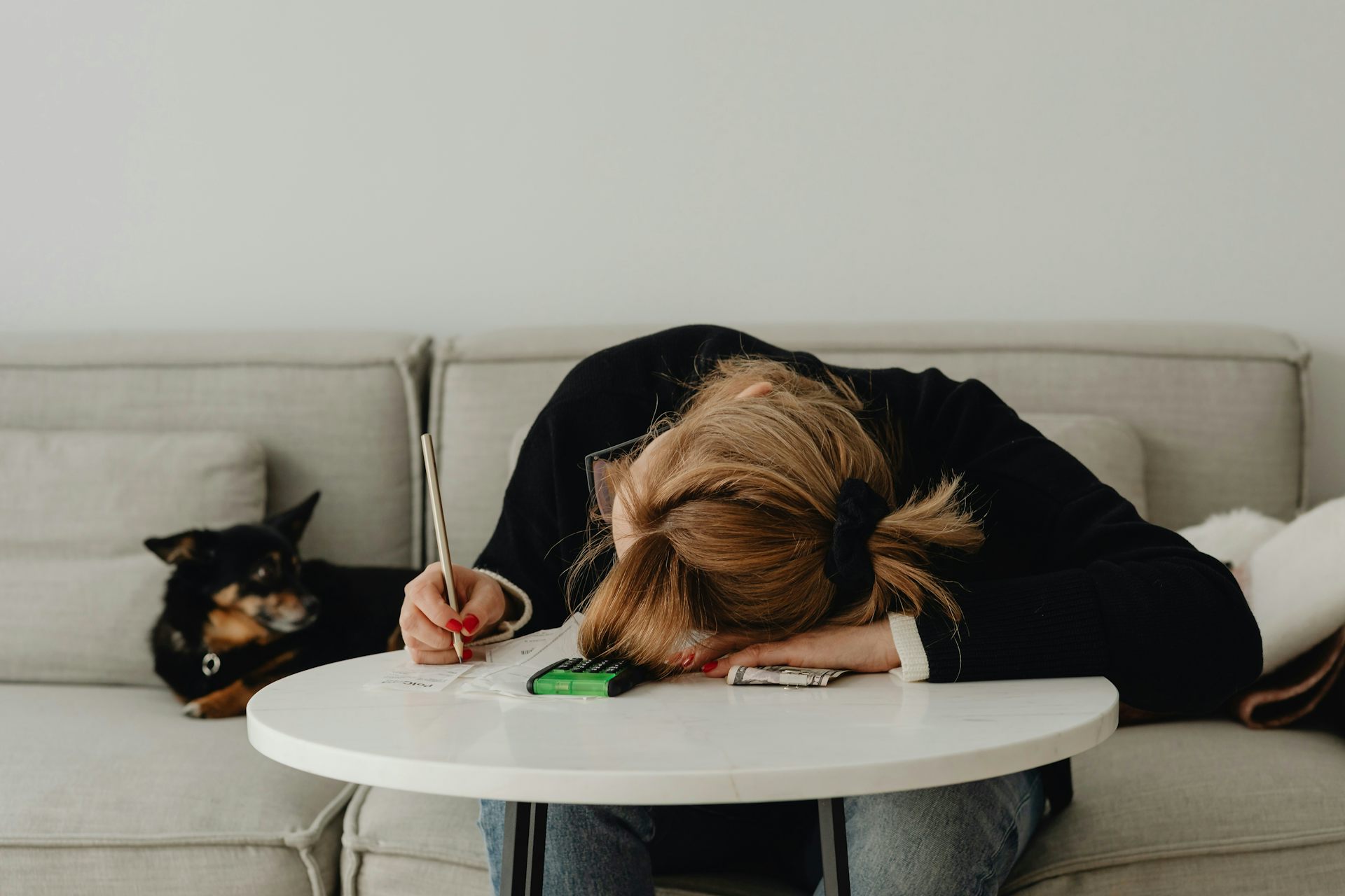 Una mujer sentada con la cabeza gacha sobre una mesa.