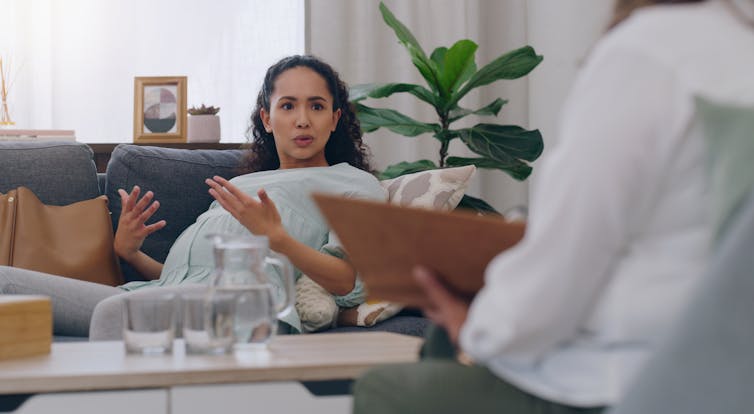 A concerned pregnant woman speaks with her doctor or nurse, who holds a clipboard.